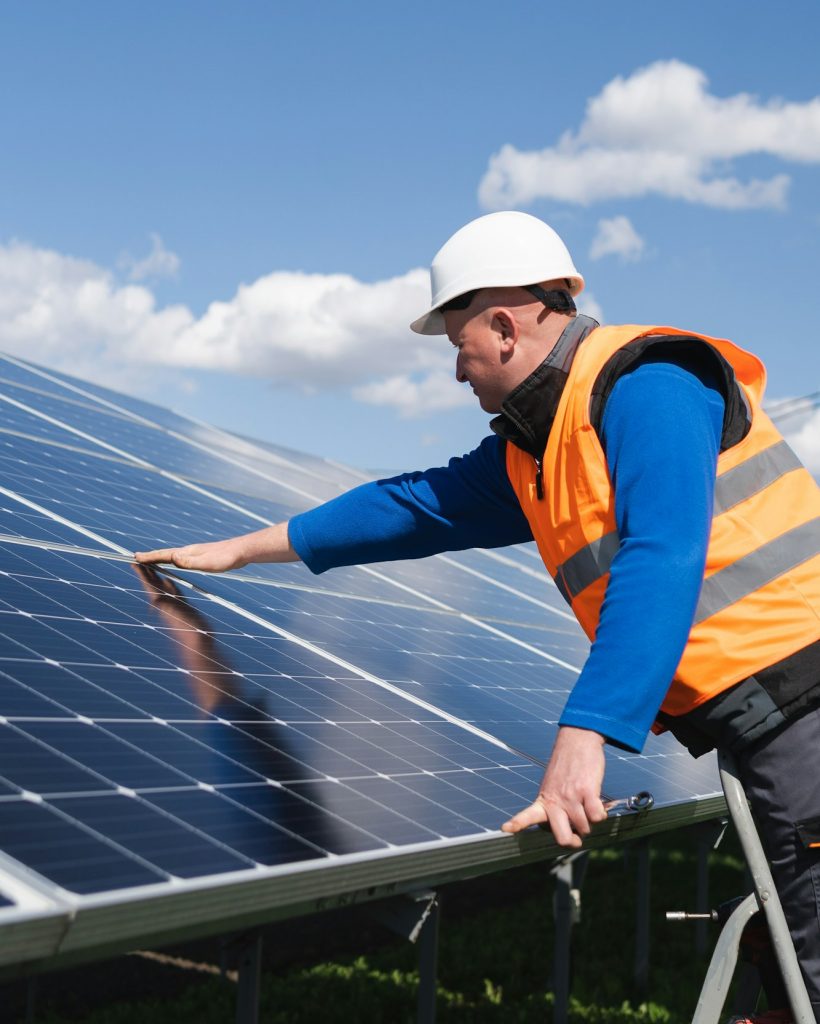 Solar power plant worker on stepladder makes a visual inspection of solar panels